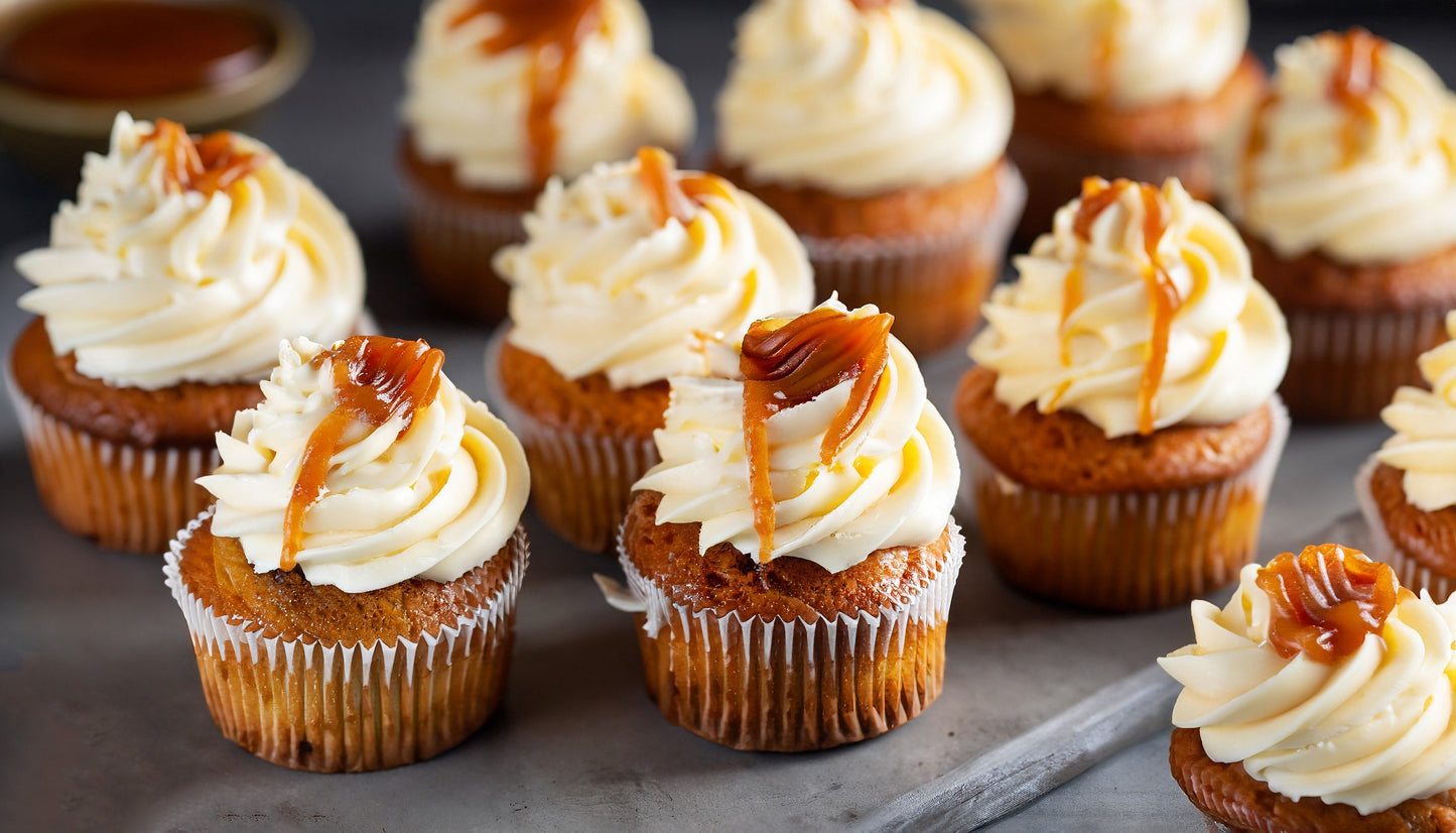 A bunch of cupcakes lined up with caramel drizzle on top